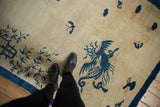 Detailed pictorial cobalt blue phoenix on an antique ivory Peking rug.