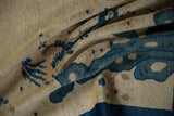 Textured close-up of folded antique Peking rug, ivory pile with cobalt blue pictorial design.