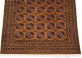 Vintage Ersari carpet detail: geometric border, medallions, and germinating plant motif in ochre, navy.