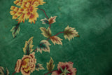 Art Deco floral spray in saffron yellow, blush, and wine red on an emerald green field.