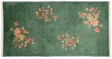 Embossed floral spray and dark copper green pile on a Nichols Art Deco rug corner.