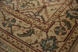 Agra carpet corner detail with ivory, wine red trellis, olive green plants, and soft fringe.