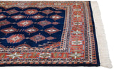 Ivory fringe, navy blue selvage, and rust geometric border of the Indian Turkmen rug.