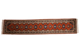 Vintage Indian Turkmen runner featuring repeating medallions and hook motifs in rust, navy, and ivory.