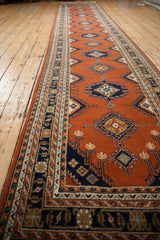 Intact side selvage and navy border with hook and latch motifs on a rust field.