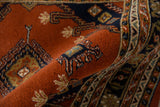 Plush rust pile texture with distinct navy and ivory geometric patterns on the vintage Turkmen rug.