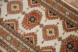 Repeating rust and navy hook and latch motifs on the vintage Indian Turkmen rug.