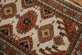 Indian Turkmen rug with geometric rust, navy, and ivory hook and latch motifs.