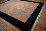 Corner detail of Art Deco rug: pastel floral sprays on apricot, jet black border, fringe.