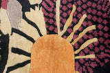 Art Deco Indian rug close-up: orange starburst with black and raspberry floral patterns.