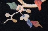 Detail of Indian Art Deco rug with contrasting rose and ivory floral vines on navy black.