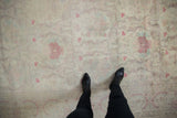 Looking down at the distressed texture and pale raspberry florals on a vintage Kerman design carpet.