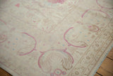 Angled corner view of a distressed vintage rug with a plush pile and soft raspberry red florals.