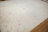 A sweeping view across the vintage distressed carpet's ivory field and repeating floral pattern.