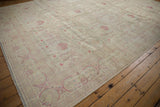 Expansive ivory field of a distressed Kerman carpet with repeating raspberry floral motifs.