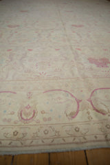 Surface-level view of a distressed vintage carpet, highlighting the ivory field and raspberry motifs.
