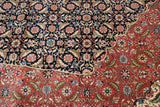 Scalloped contour of a navy Herati field meeting the brick red floral border on a vintage rug.