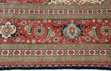 Intricate palmettes and scrolling vines in the brick red border of a vintage Bulgarian Tabriz carpet.
