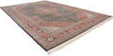 Angled perspective of a vintage Bulgarian rug with a navy Herati field and rich terracotta border.
