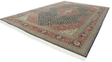 Angled view of an oversize Bulgarian Tabriz carpet with a navy Herati field and terracotta floral borders.