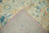 Folded corner of the vintage carpet revealing its hand-knotted back and low, distressed pile.