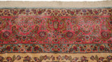 Close-up of a vintage Kerman carpet showing the fine millefleur border and original fringe.
