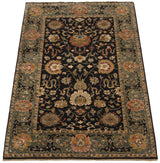 Angled perspective of a traditional Agra carpet with elaborate palmettes on a charcoal black field.