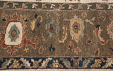Detailed view of the Serapi carpet border with sprawling vinery in olive and copper tones.