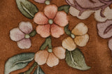 Dimensional piled carving of ornate blush, rose, and green foliage on Art Deco rug.