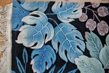 Vintage jungle carpet corner, sculpted blue and oxidized green leaves, rose accents, fringe.