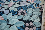 Raised oxidized green leaves, pink blossoms, blue accents, black jungle carpet, natural fringe.