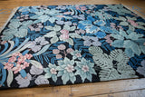 Modern, relief-carved jungle carpet with pastel leaves and blossoms on black.