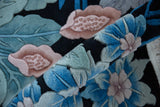 Rolled vintage jungle carpet revealing sculpted blue, green, and pink floral pile.