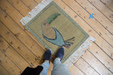 Colorful toucan's head, eye, and patterned vine-and-bud border of a pictorial Armenian rug.