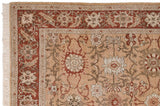 Corner view of a vintage Armenian rug showing its rust floral border and original cream fringe.