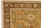 Corner of a vintage Armenian carpet showing a terra cotta border with floral palmettes and a golden field.