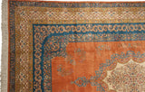 Corner of a vintage Kerman carpet showing sky blue and beige floral borders and a pale terra cotta field.