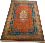 Angled view of an oversize Bulgarian carpet with a terracotta and blue Rococo Kerman design.