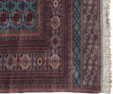 Corner detail of a Bokhara carpet showing intricate geometric borders and original side cord selvage.