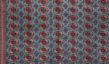 Detailed view of the plush wool pile showing repeating gul medallions in red, rust, and navy.