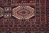 Finely knotted gul medallion in rust, navy, and ivory on a plush vintage Pakistani Bokhara carpet.
