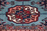Close-up on the plush, even wool pile of a Bokhara gul medallion in red and navy.
