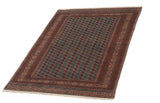 A vintage Bokhara carpet seen from a long angle, emphasizing its plush pile and repeating gul design.