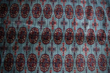 Fine Bokhara weave with red and navy gul medallions on a plush powder blue wool pile.