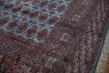 Intricate geometric border in red and navy alongside the powder blue field of a fine Bokhara carpet.