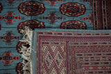 Corner view contrasting the soft powder blue pile and the intricate geometric weave on a Bokhara rug's back.