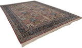 Full-length angled view of a vintage Kerman design carpet with pictorial panels and a wide, navy floral border.