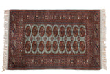 Vintage Pakistani Bokhara rug with repeating gul medallions over a powder blue field with rust borders.