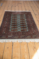 Angled perspective showing the full length and repeating gul pattern of a vintage Bokhara rug.