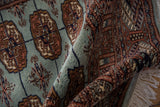 Lustrous, silk-like wool pile of a vintage Bokhara rug folded to show its fine, dense weave.